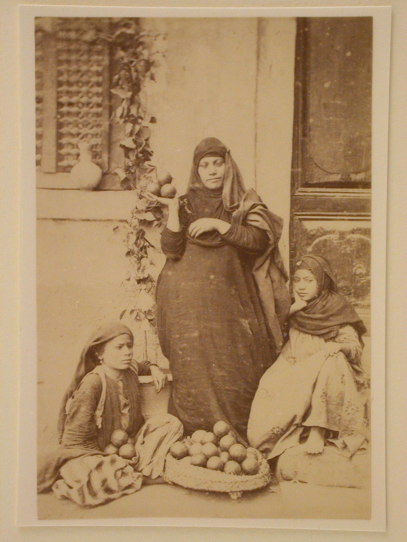 Three Egyptian women with fruit, posed in a doorway