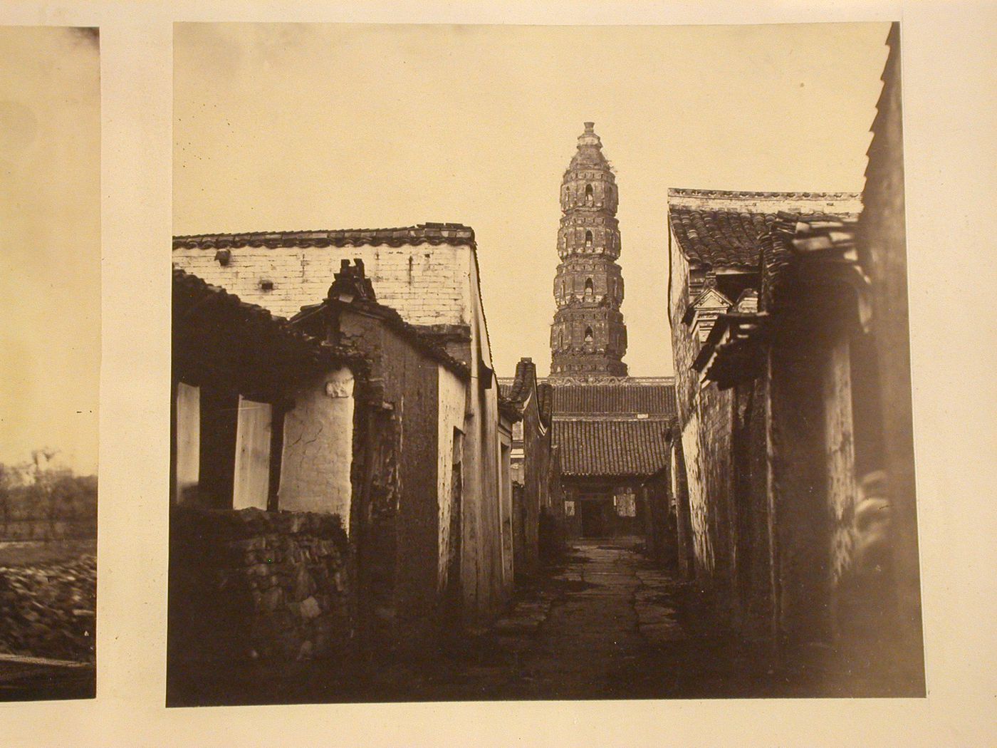 View of an alley and the upper part of the Heaven Conferred Pagoda [Tianfeng Ta], in the background, Ningpo (now Ningbo Shi), Cheh-kiang Province (now Zhejiang Sheng), China