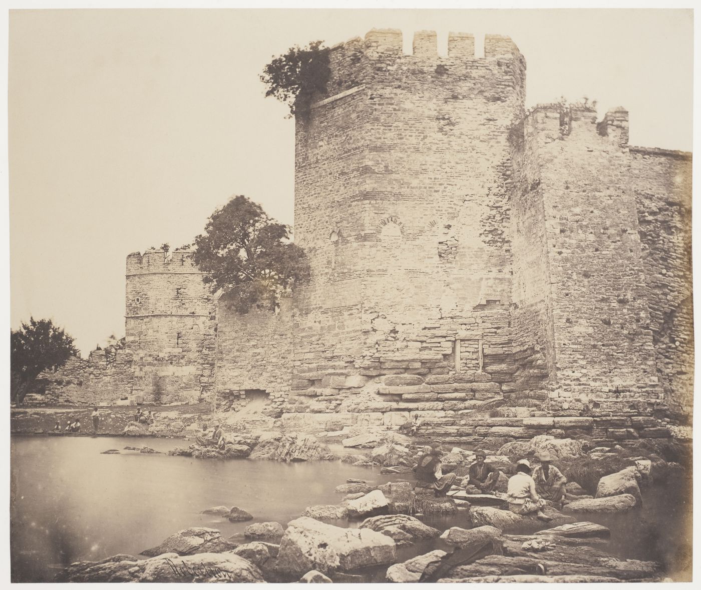 View of a section of the Theodosian Wall showing wall towers with people and a body of water in the foreground, Constantinople (now Istanbul), Ottoman Empire (now in Turkey)