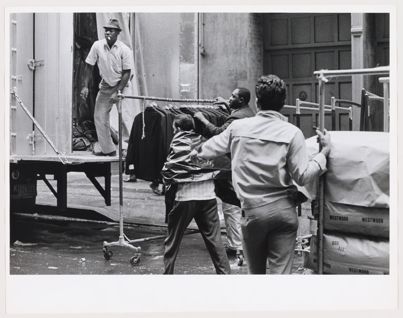 Group portrait of workers using rolling garment racks on the street, West 37th Street, Manhattan, New York City, New York