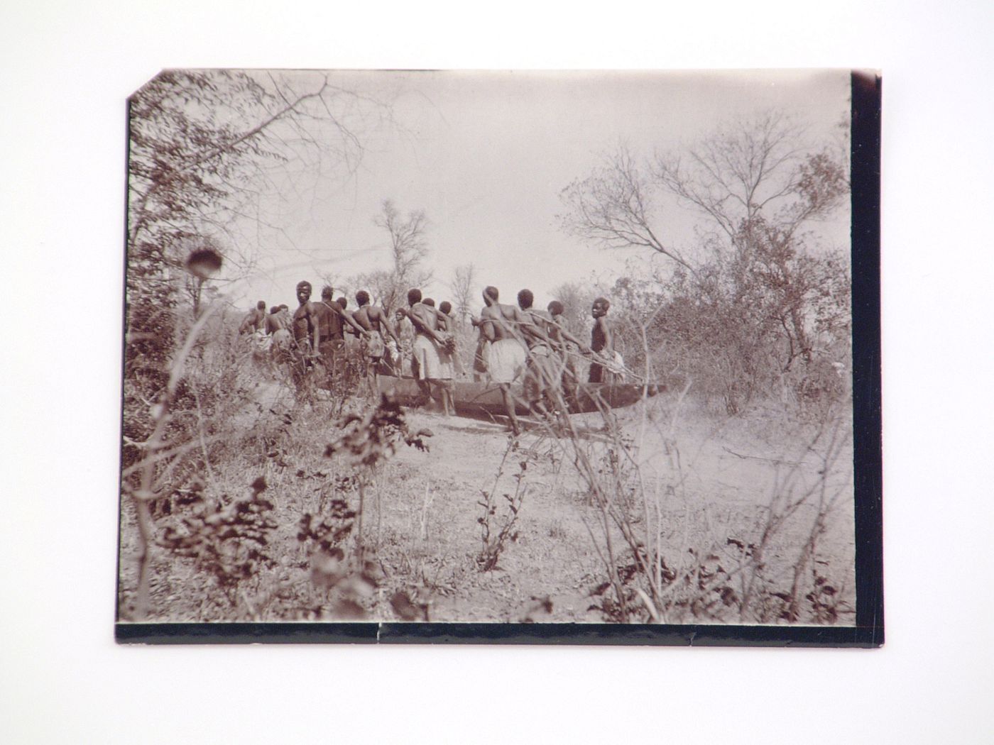 View of a group of people carrying a mokoro (wooden dugout canoe) boat, near the Zambezi River