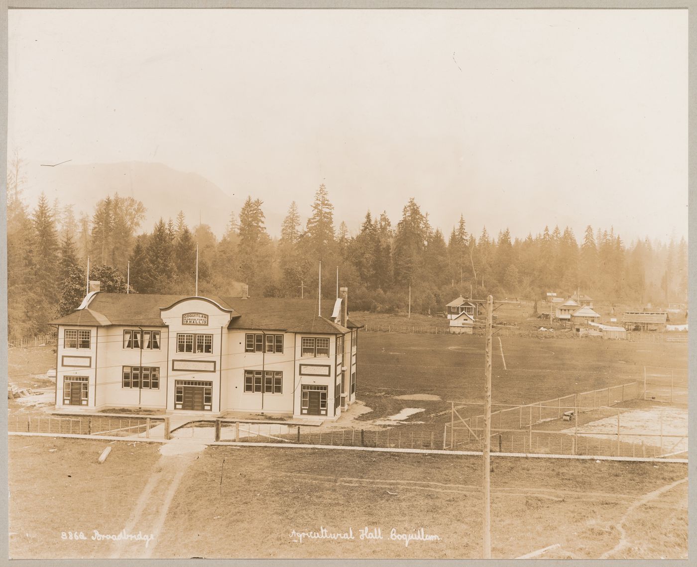 View of the principal façade of the Agricultural Hall with Greenwood housing development under construction in the background, Coquitlam (now Port Coquitlam), British Columbia