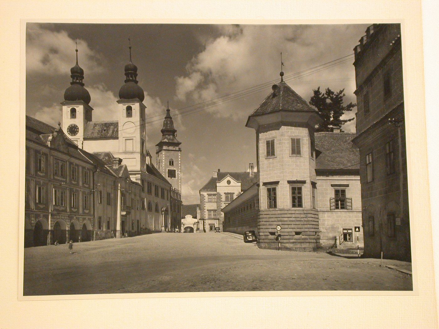 View towards the entrance of Telc Château showing the Námestí Míru [Town Square], Church of Jesus' Name, tower of St. James Church and a wing (now the Art Gallery Jana Zrzavého) of the Château in the foreground, Telc, Czechoslovakia (now Czech Republic)