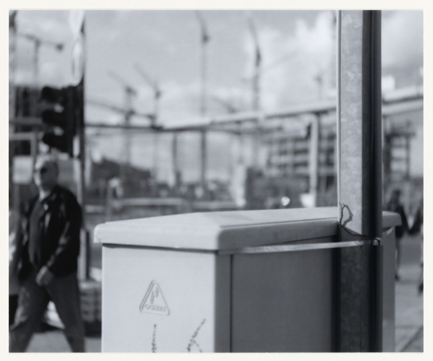 View of an electrical box, post, and a man showing building sites in the background, Berlin, Germany, from the artist book "The Potsdamer Project"