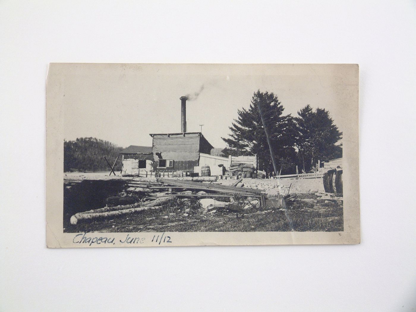 View of construction materials at the back of industrial workshop with chimney, Chapeau, Québec, Canada