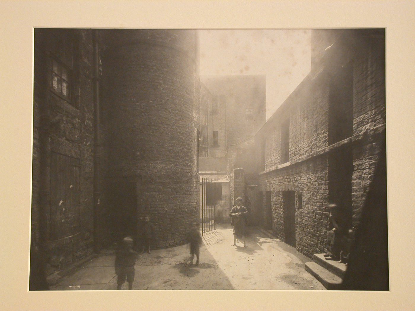 View of a courtyard with seven children, an iron gate at the rear, Glasgow, Scotland