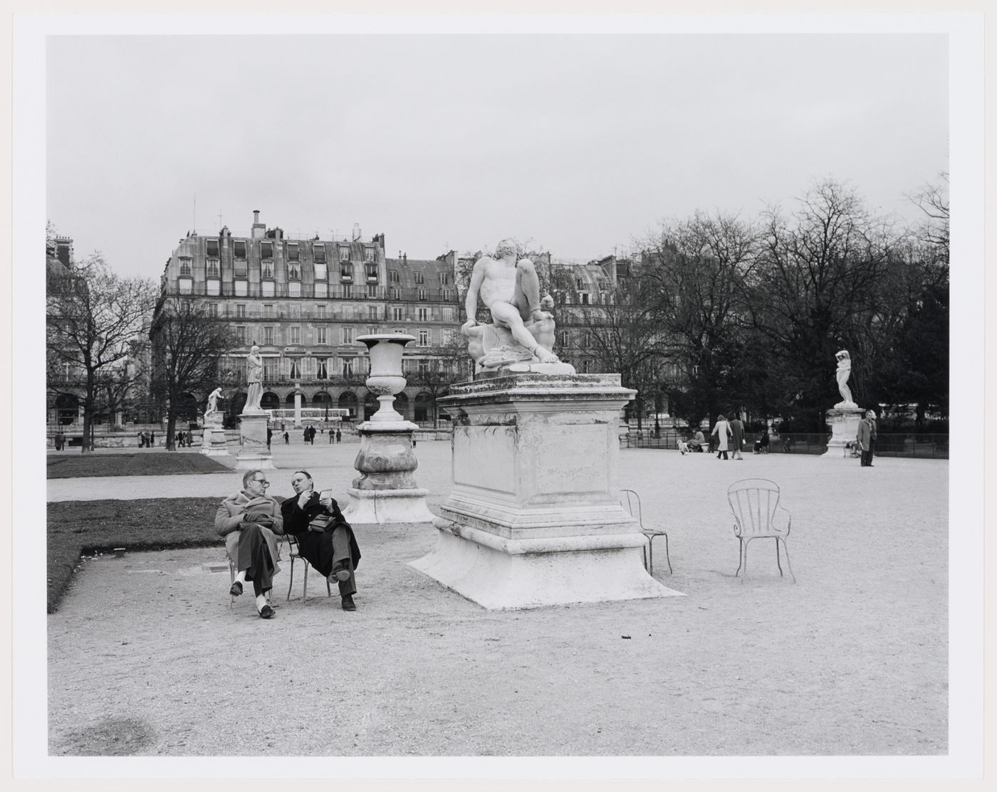 Two men sitting, talking in a sculpture-lined garden, Les jardins des Tuileries, Paris, France