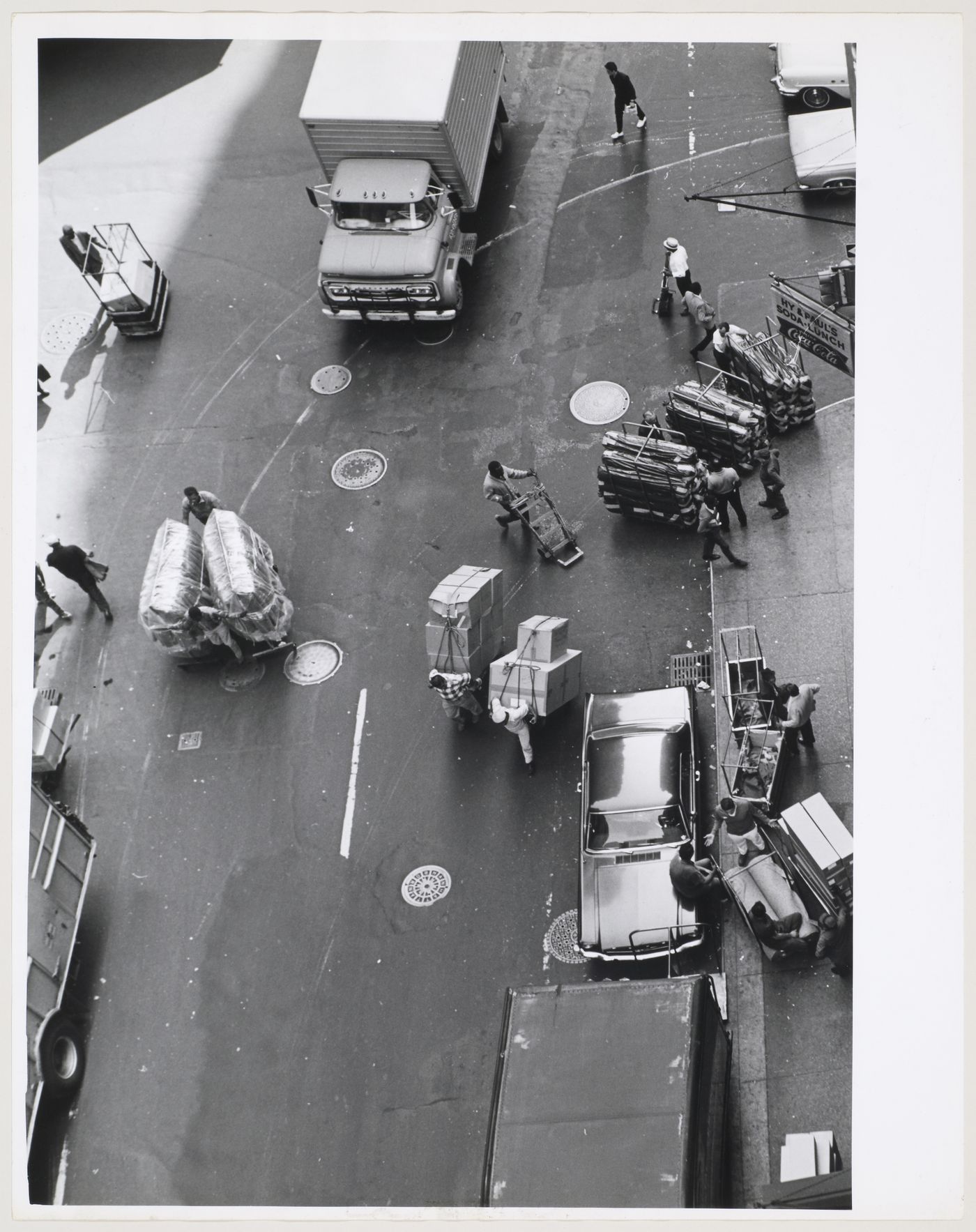 Aerial view of traffic and workers moving freight and using handcarts on West 37th Street, Manhattan, New York City, New York