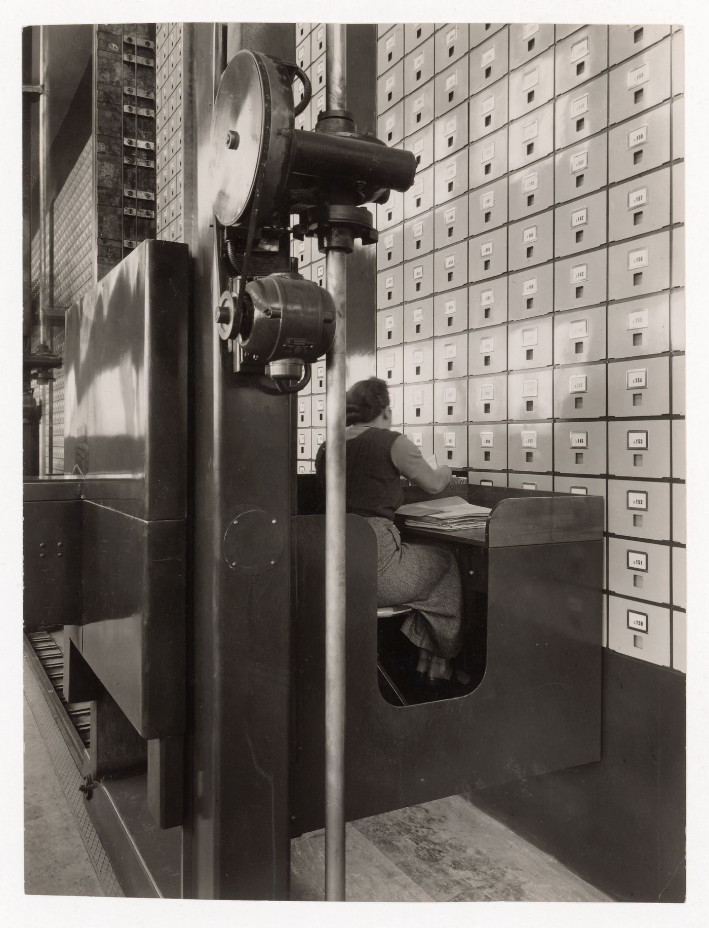 Interior view of the Central Social Insurance Institution showing a woman working at a mobile work station used to access the card catalog drawers, Prague, Czechoslovakia (now Czech Republic)