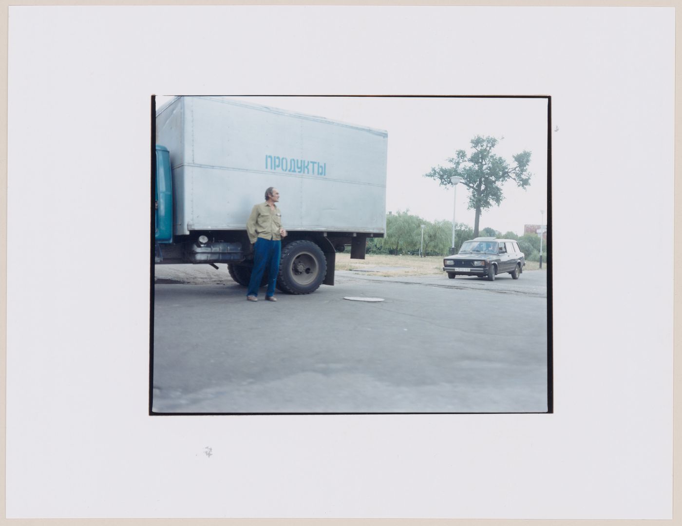 View of a truck, an automobile and a man on a road, Svetlyy, Kaliningradskaia oblast', Russia (from the series "In between cities")