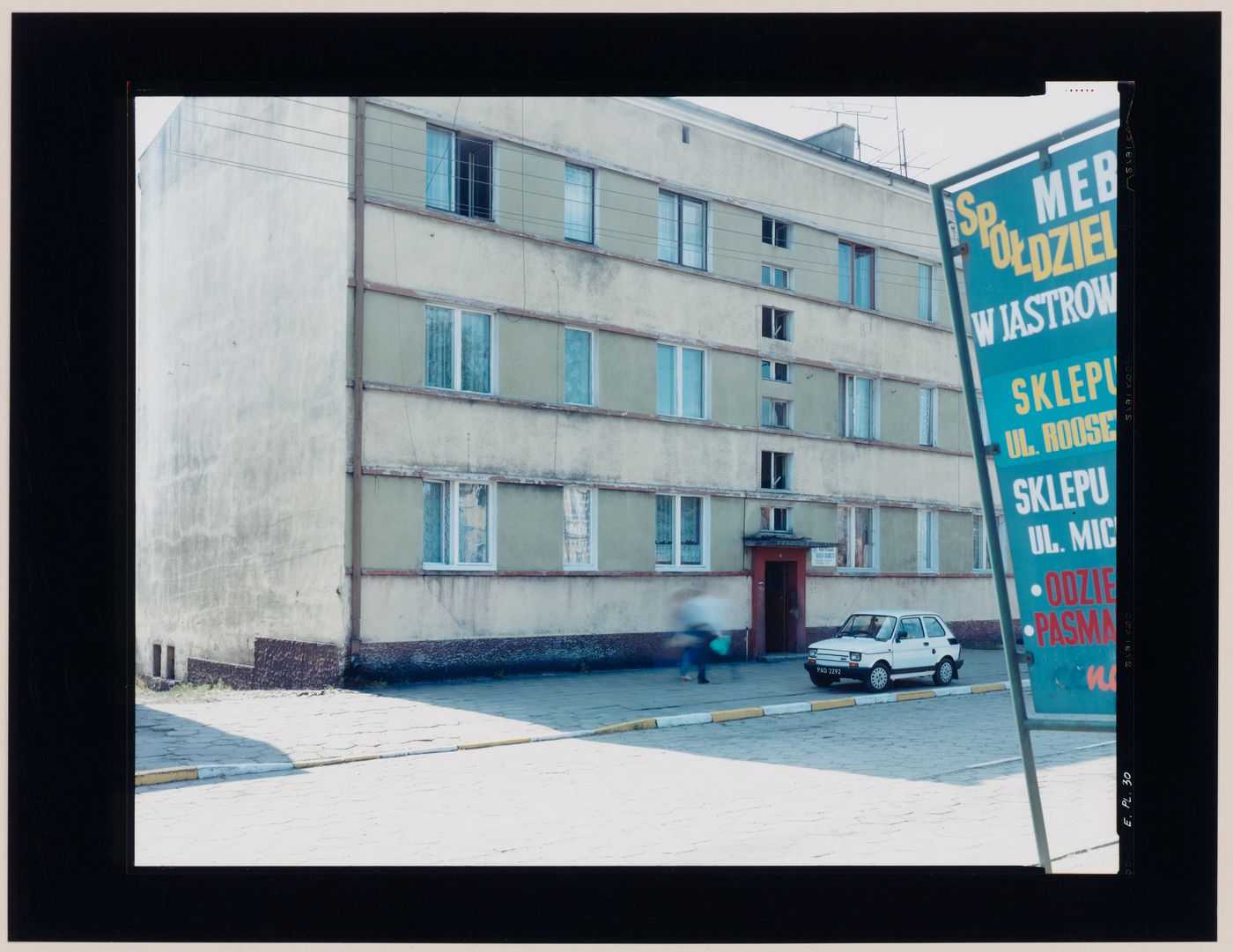 View of an apartment house, a street and a sign showing a parked automobile, Jastrowie, Poland (from the series "In between cities")