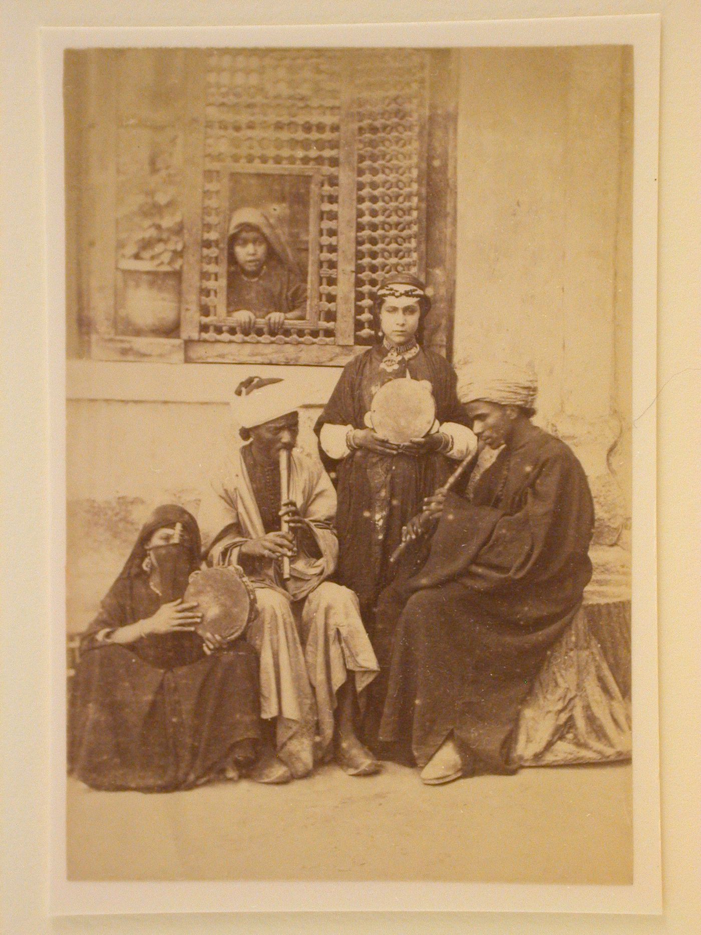 Four Egyptian musicians playing before a window screen