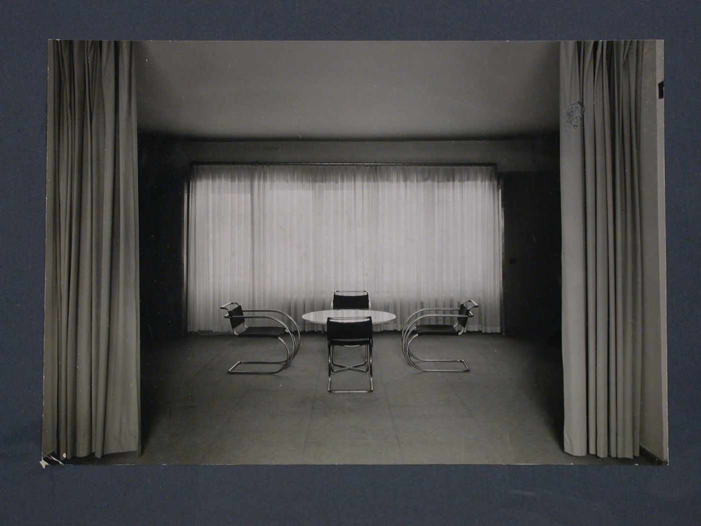 Interior view of a curtained room with a table designed by Marcel Breuer and armchairs by Mies van der Rohe, Germany