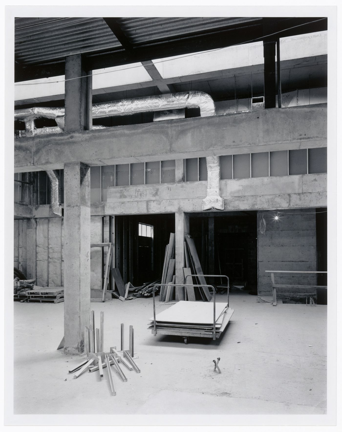 Interior view of the Entrance Court showing a column, air ducts, and a wheelbarrow with building materials, Canadian Centre for Architecture under construction, Montréal, Québec