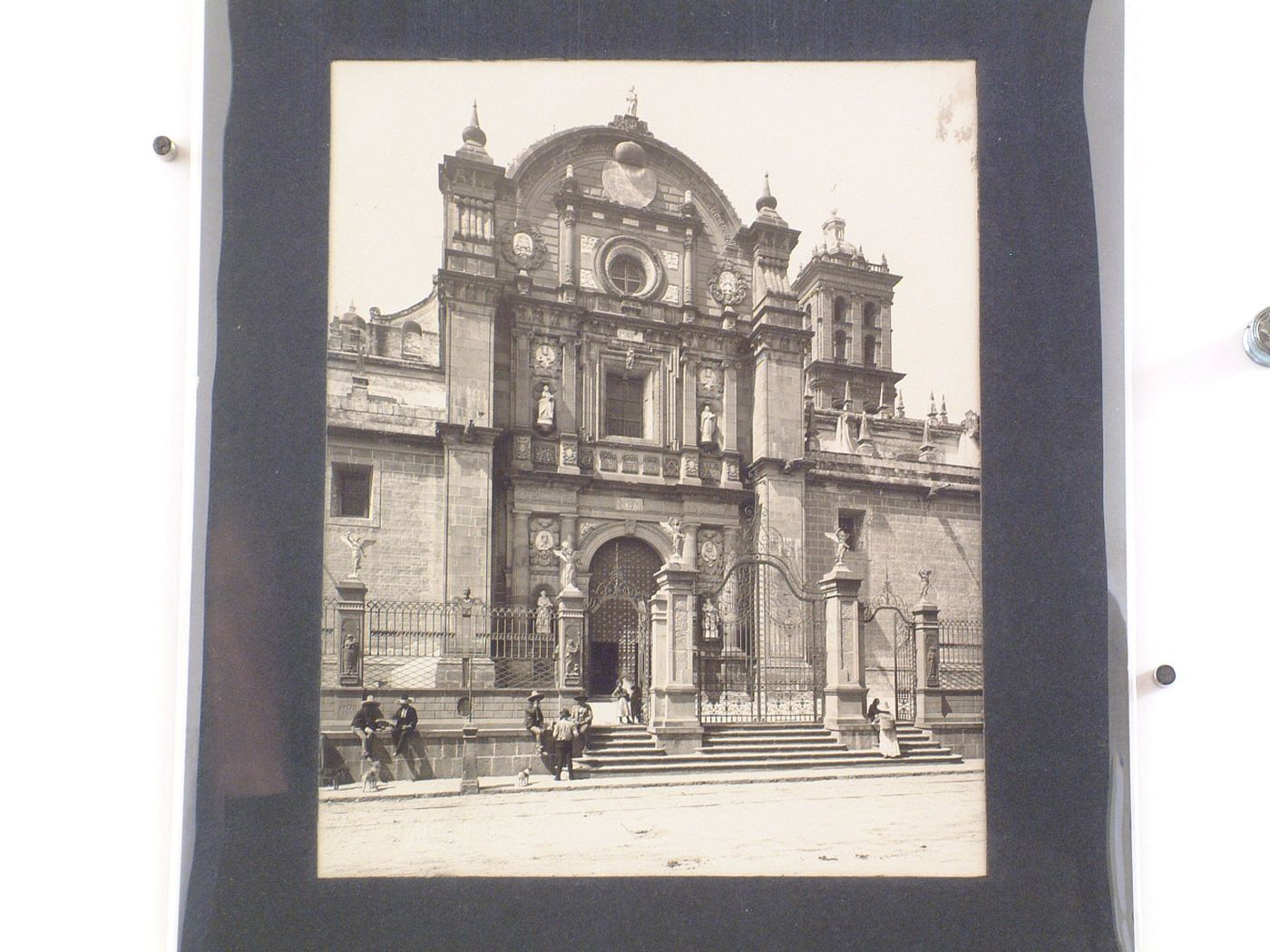 View of the northern façade of the Catedral de Puebla showing a gateway and part of the fence surrounding the atrio with people in the foreground, Mexico