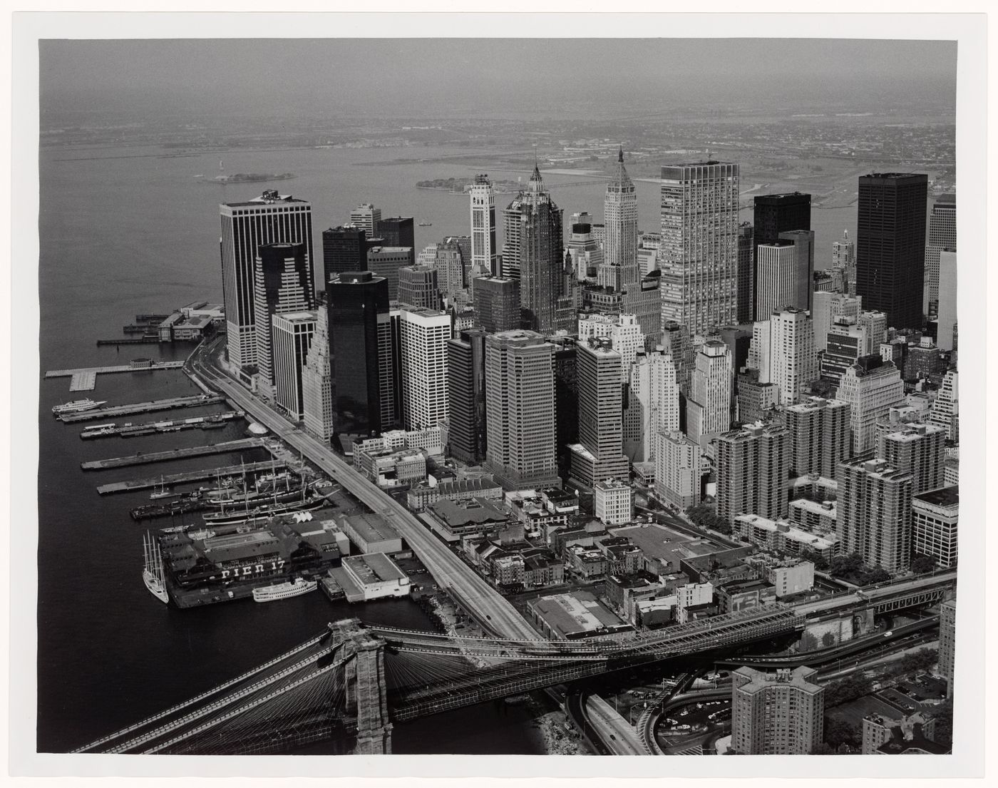 Aerial view showing lower Manhattan skyscrapers, including the Chase Manhattan Bank and The 40 Wall Street, with East River piers, the Brooklyn Bridge, and, in the background, Liberty Island and Ellis Island, New Jersey and New York, United States