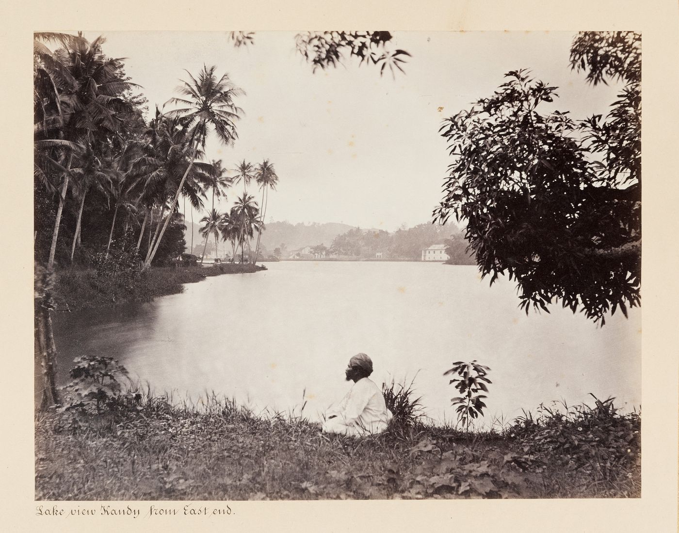 View of Kandy Lake from the east end with a man in the foreground, Kandy, Ceylon (now Sri Lanka)