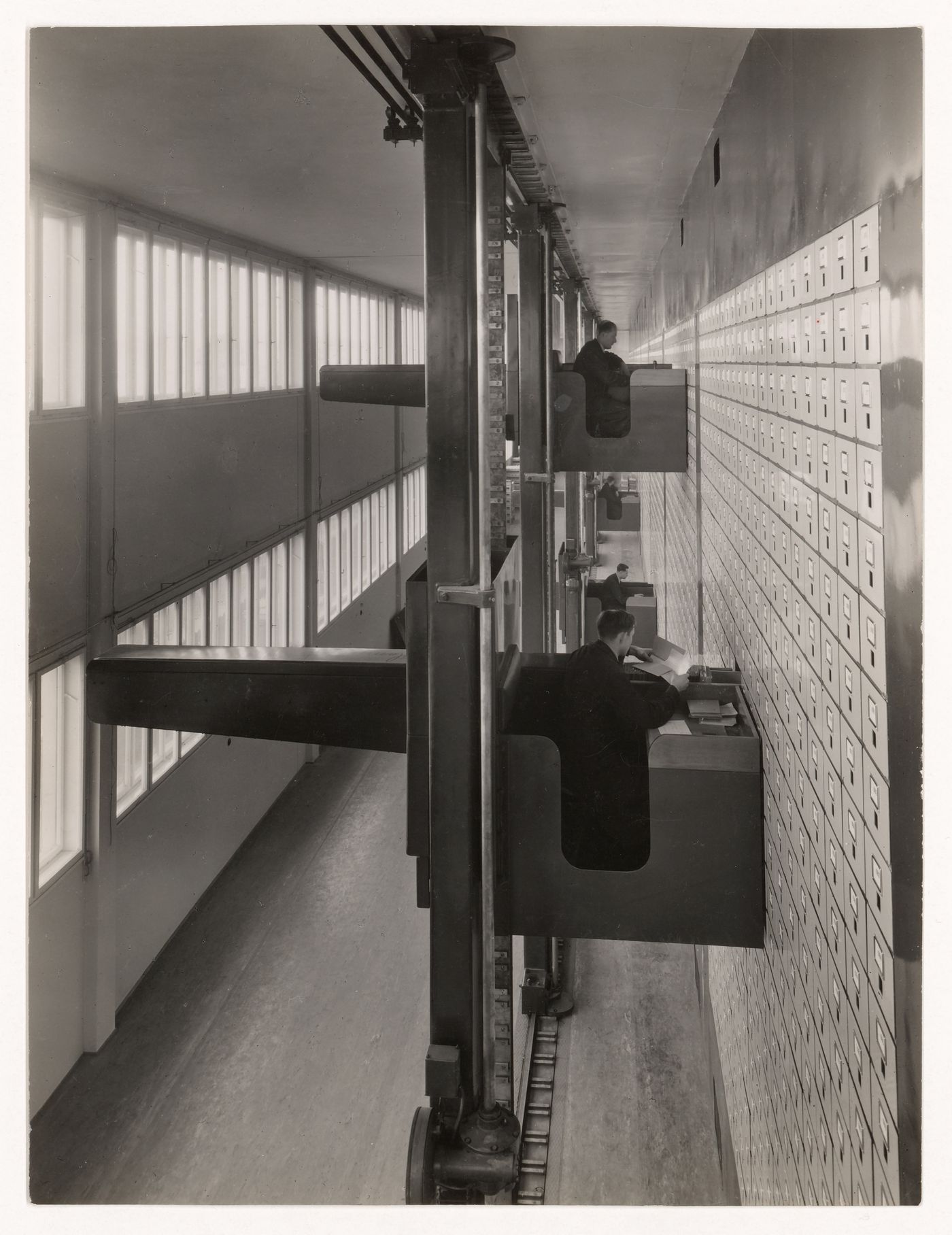 Interior view of the Central Social Insurance Institution showing men working in mobile work stations used to access the card catalog drawers, Prague, Czechoslovakia (now Czech Republic)