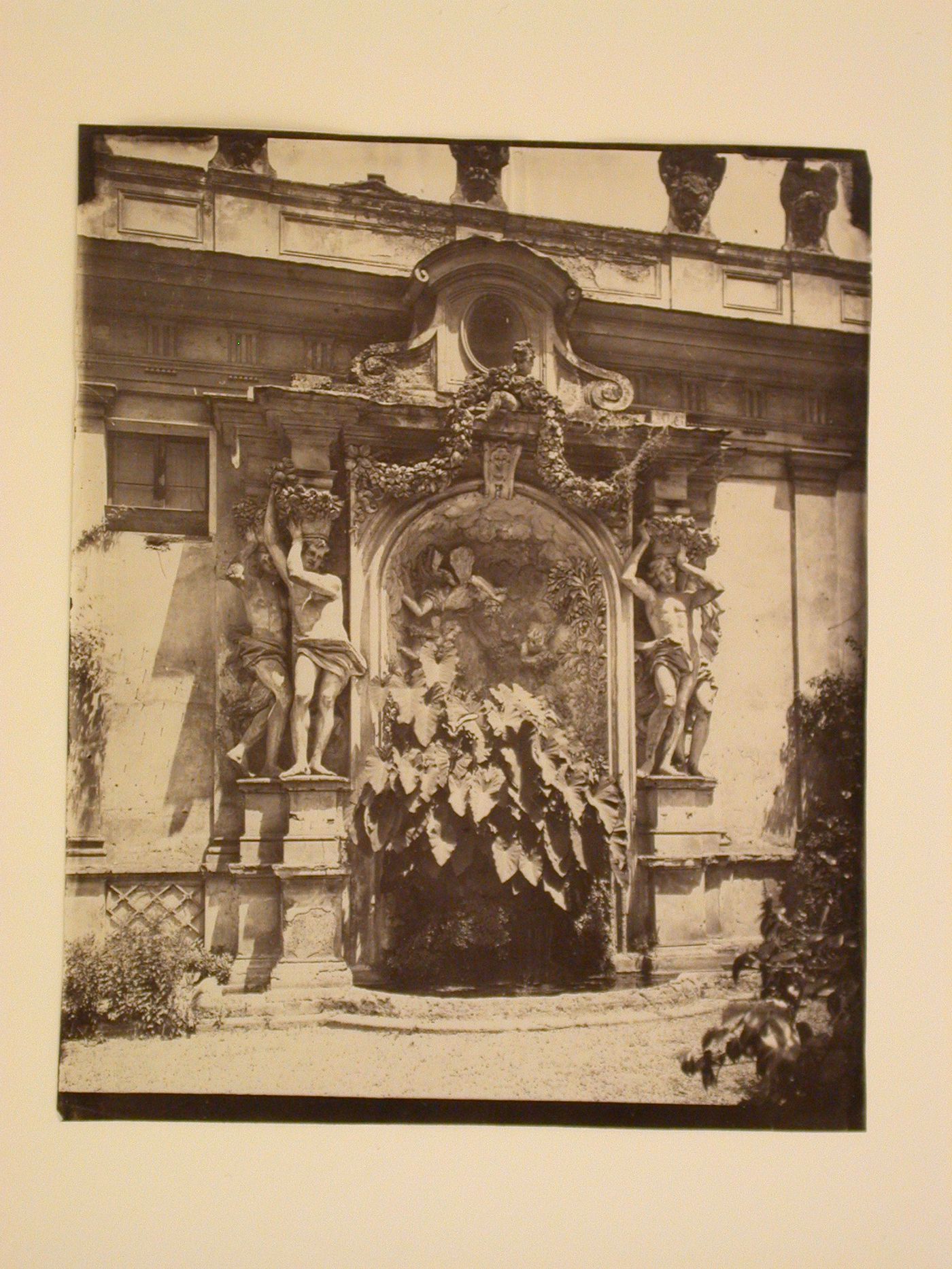 Architectural and garden study showing carved fountain and pool against wall, with urns at top, Italy