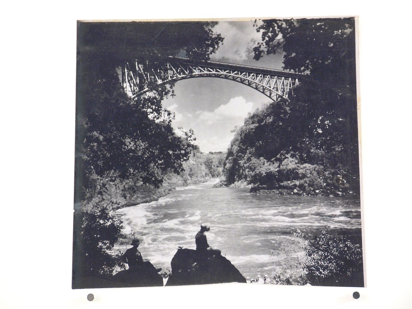 View of a group of people sitting on rocks by the Zambezi River below Victoria Falls Bridge, crossing the border between Victoria Falls, Zimbabwe and Livingstone, Zambia