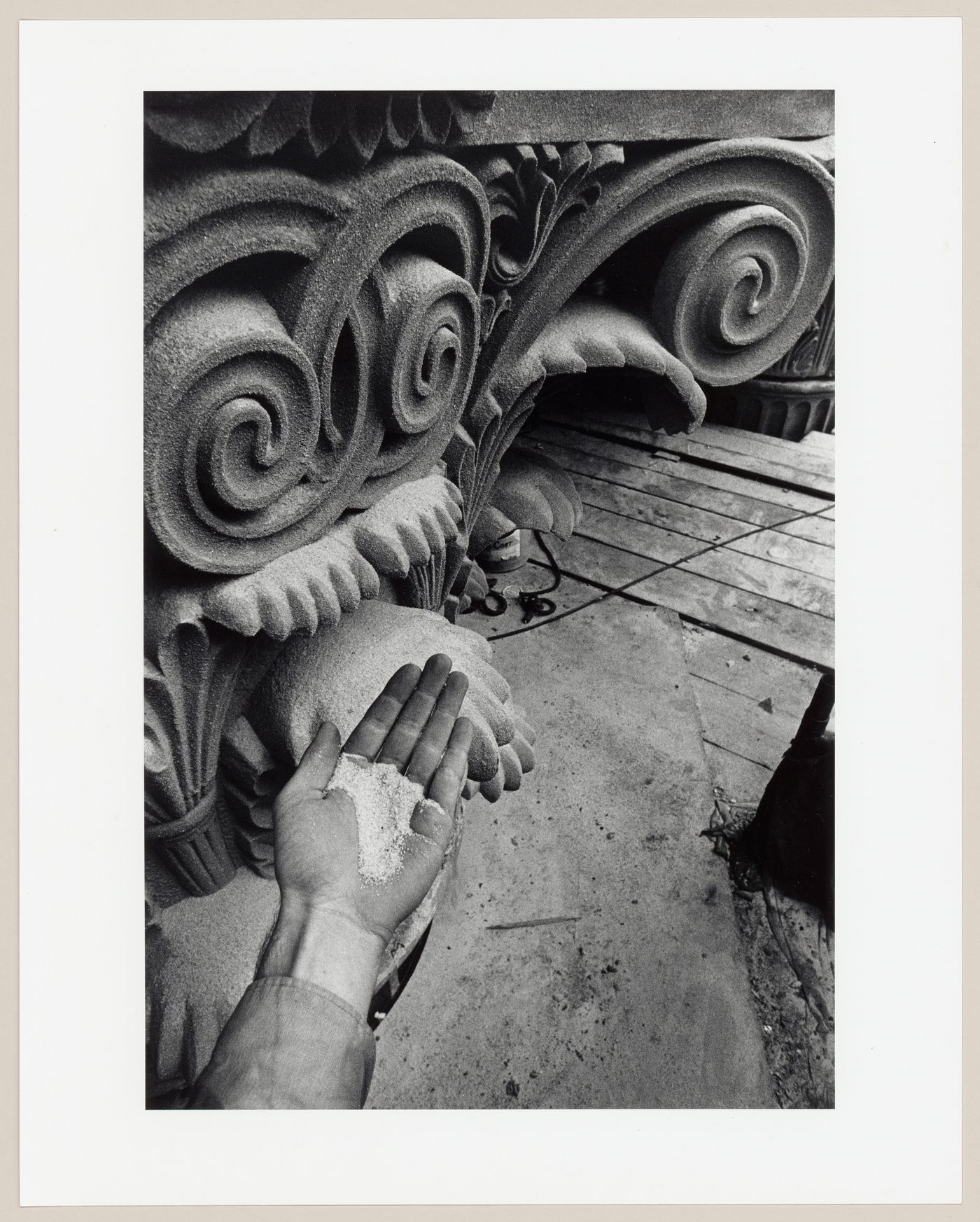Close-up view of a worker dusting the surface of an aluminium capital with silica sand during the restoration of the Corinthian capitals of the principal façade of the Head Office of the Bank of Montréal, 119 rue Saint-Jacques, Montréal, Québec