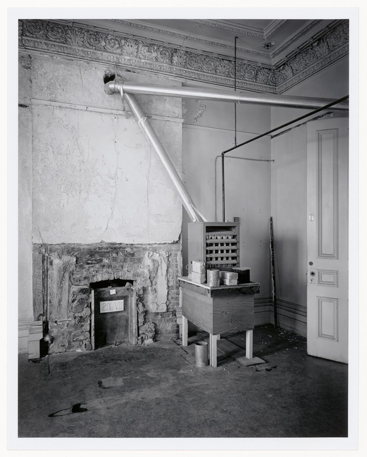 Interior view of a reception room showing a temporary furnace for construction workers and an unrestored fireplace, Shaughnessy House under renovation, Montréal, Québec