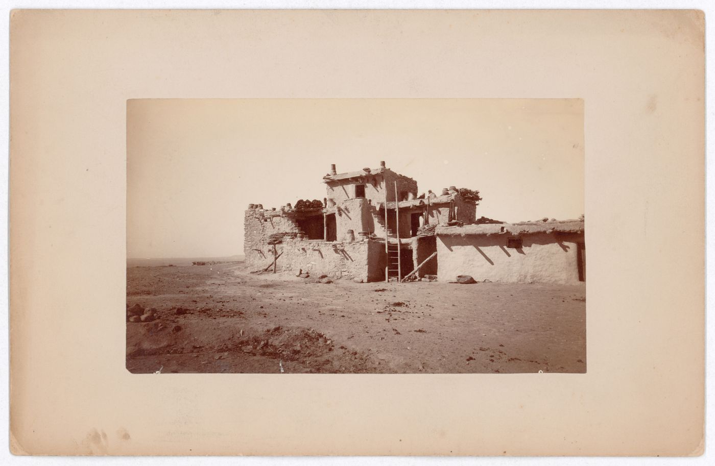 Partial view of unidentified pueblo showing terraced houses, a ladder and ceramic pots, Southwestern United States