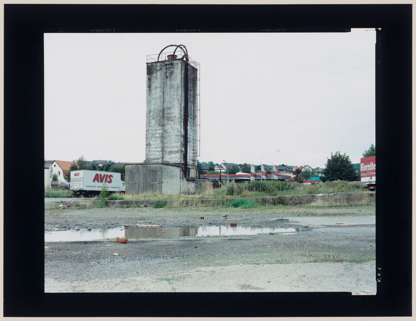 View of a silo and a vacant lot showing houses in the background, Ummendorf, near Magdeburg, Germany (from the series "In between cities")