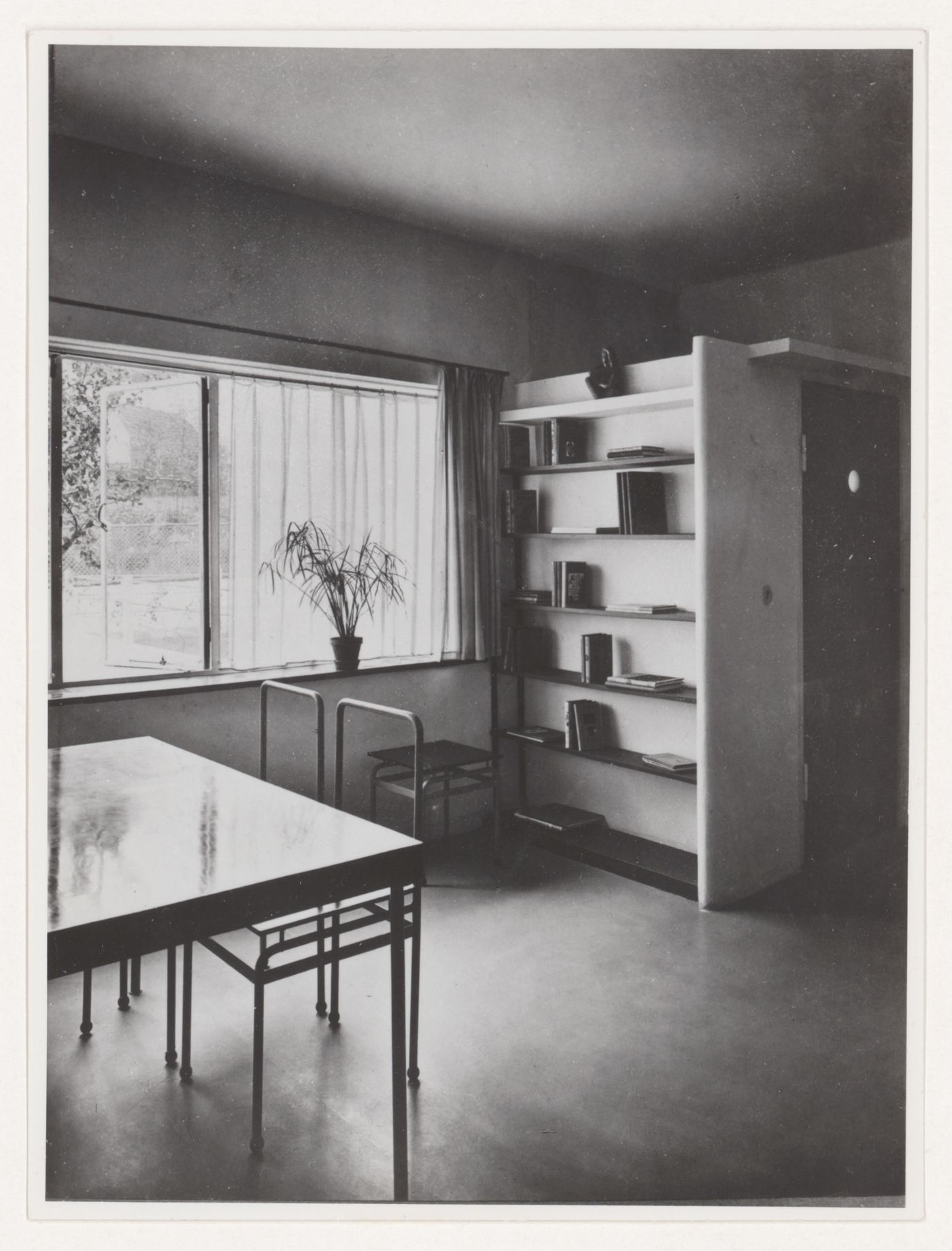 Interior view of the living room of House 8 showing a table, chairs and built-in bookshelf, Weissenhofsiedlung, Stuttgart, Germany