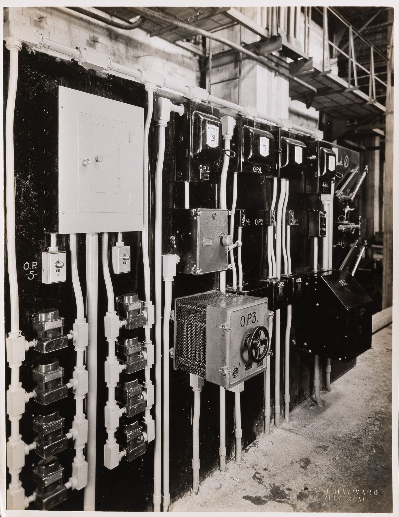 Interior view of the electrical system including electric conduits, circuit breakers and panelboards [?], possibly in the main pavilion of Université de Montréal, Montréal [?], Québec