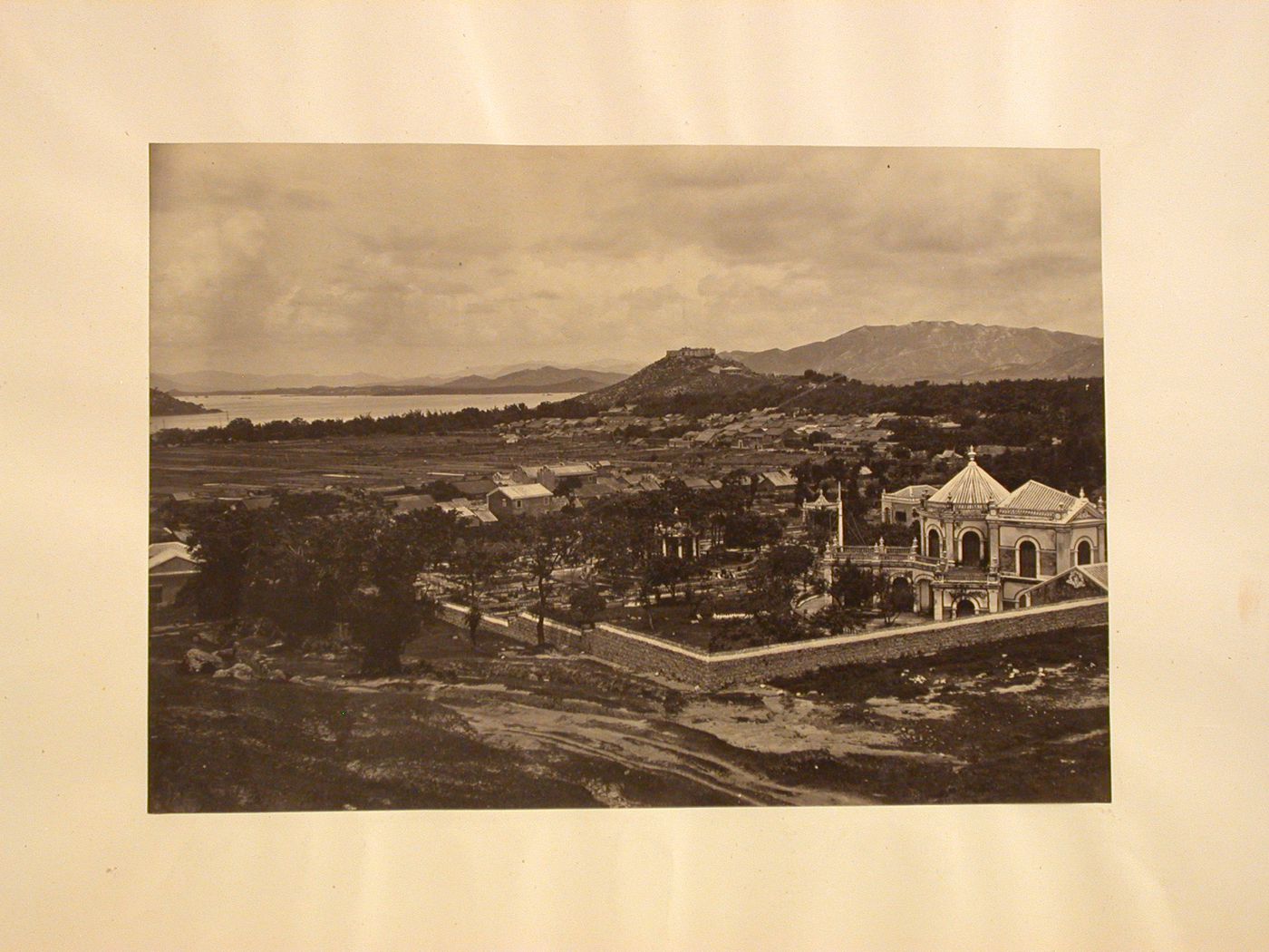 View of a house and garden compound with Mong Ha Fort on a hill in the background, taken from Guia Hill, Macau (now Macau, China)