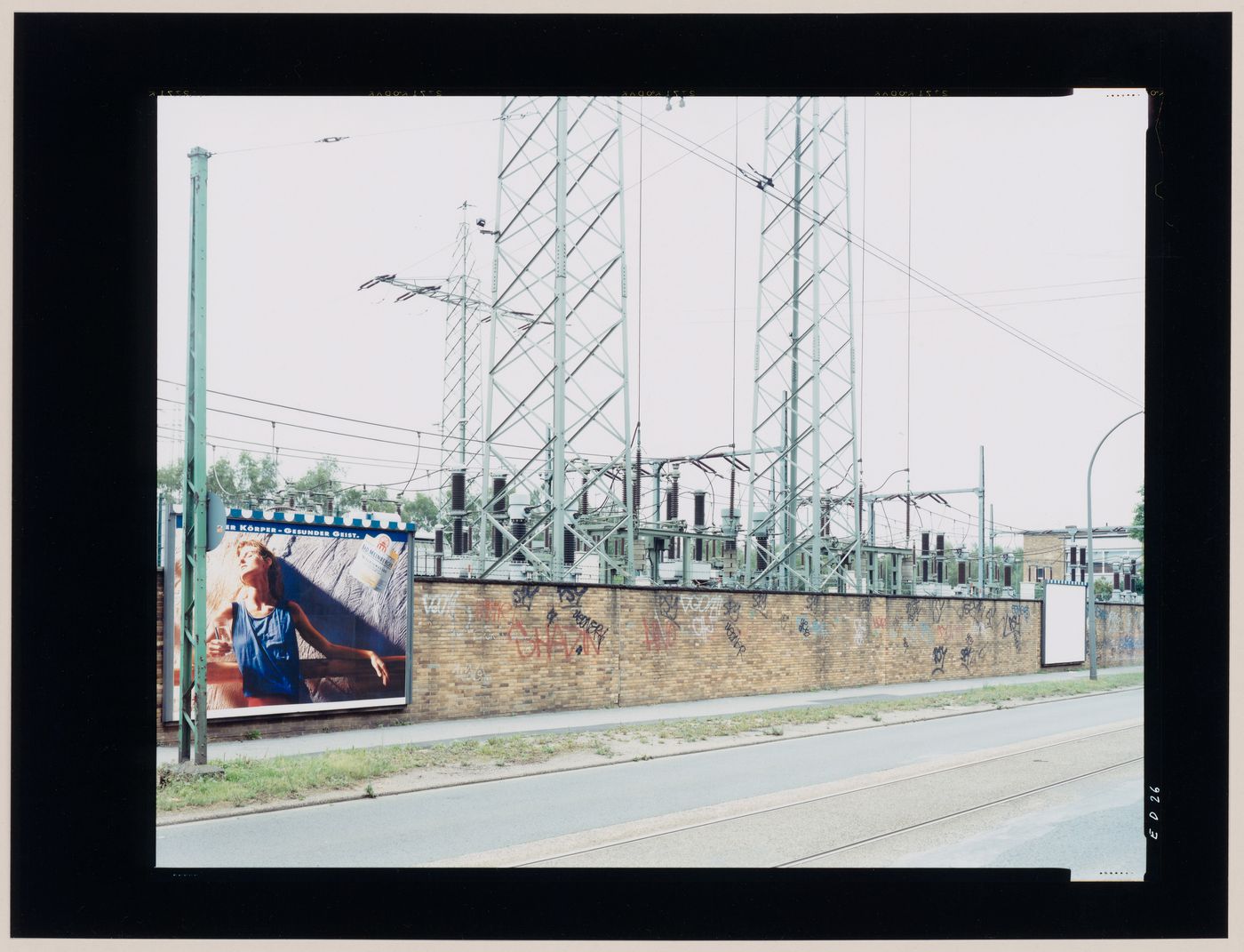 View of an electric substation, electricity pylons, a brick wall and billboards, Bochum, Germany (from the series "In between cities")