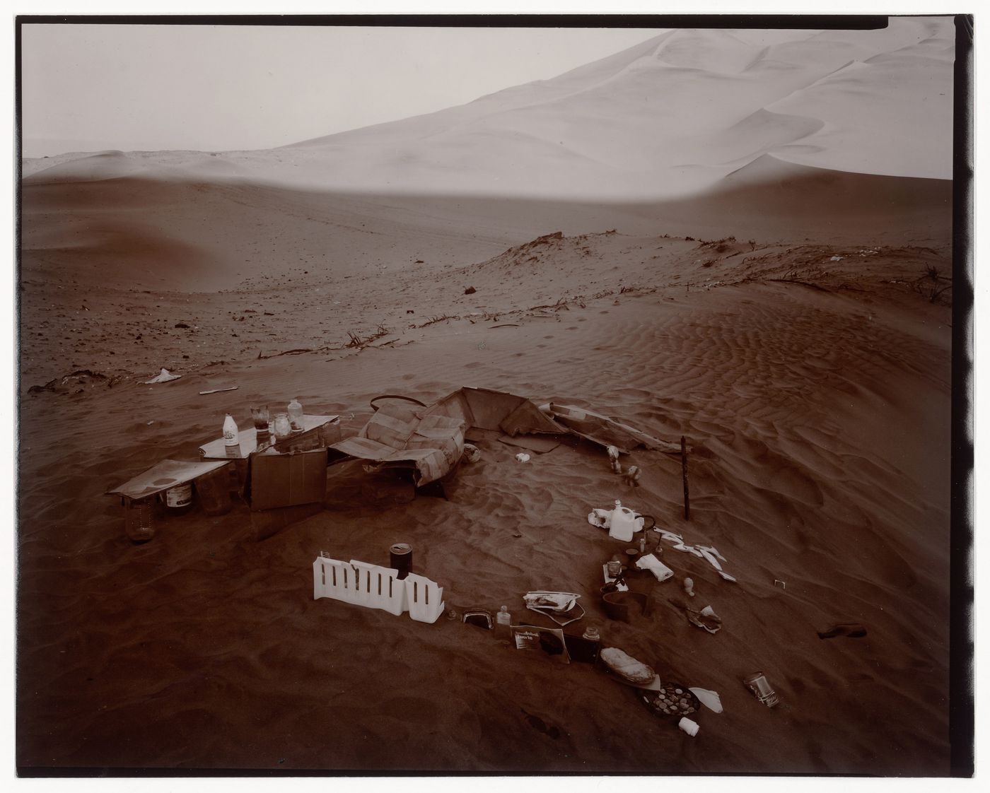 View of an arrangement of objects and refuse on sand with dunes in the background, Ica, Peru