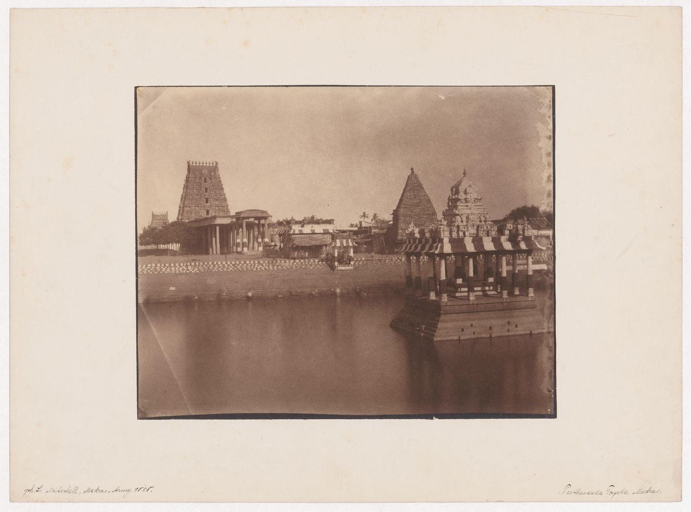 Partial view of a water tank with a pavilion showing a mandapa, shrines and gopuras in the background, Sri Parthasarathy Temple, near Madras (now Chennai), India