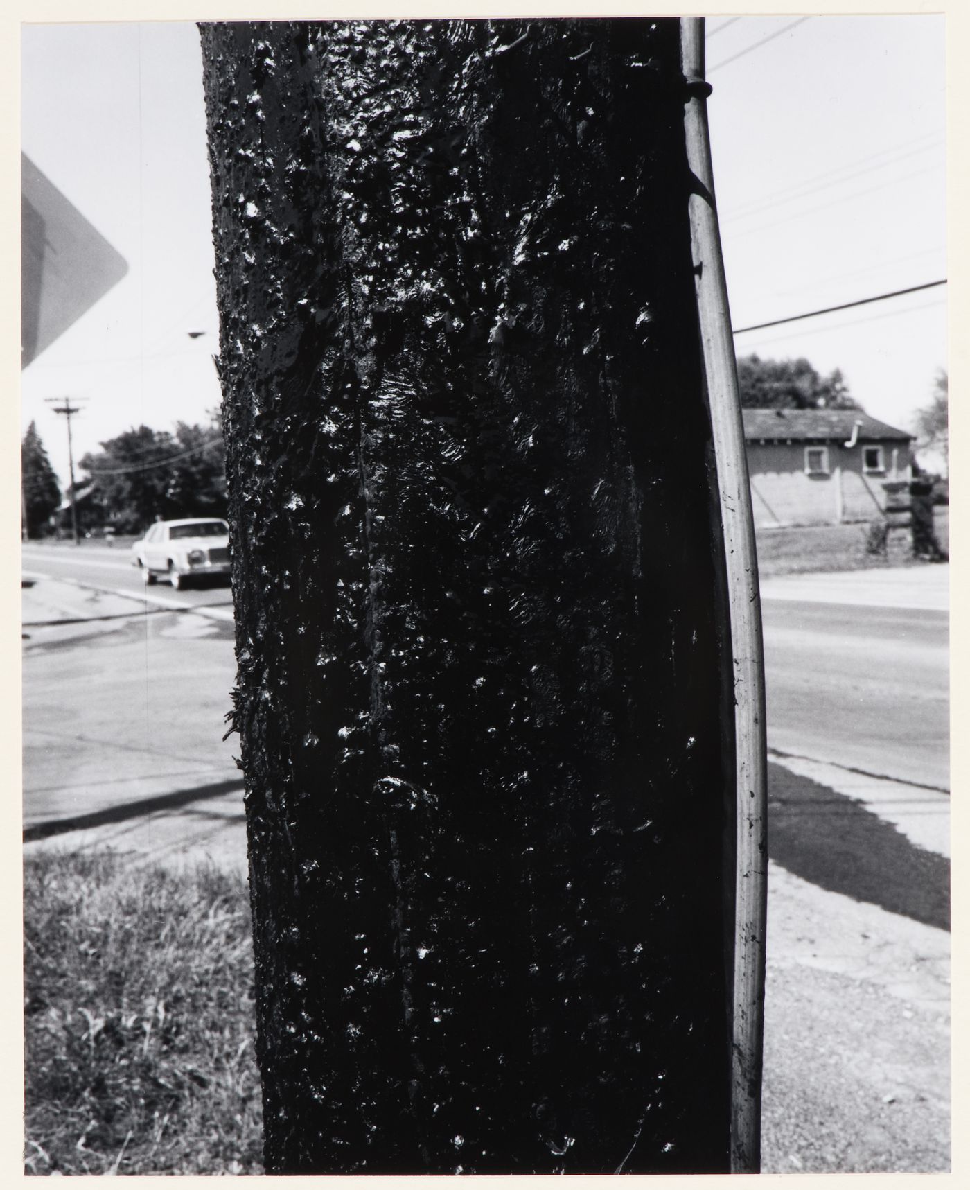 View of a utility pole showing roads, an automobile and a house in the background, New York State
