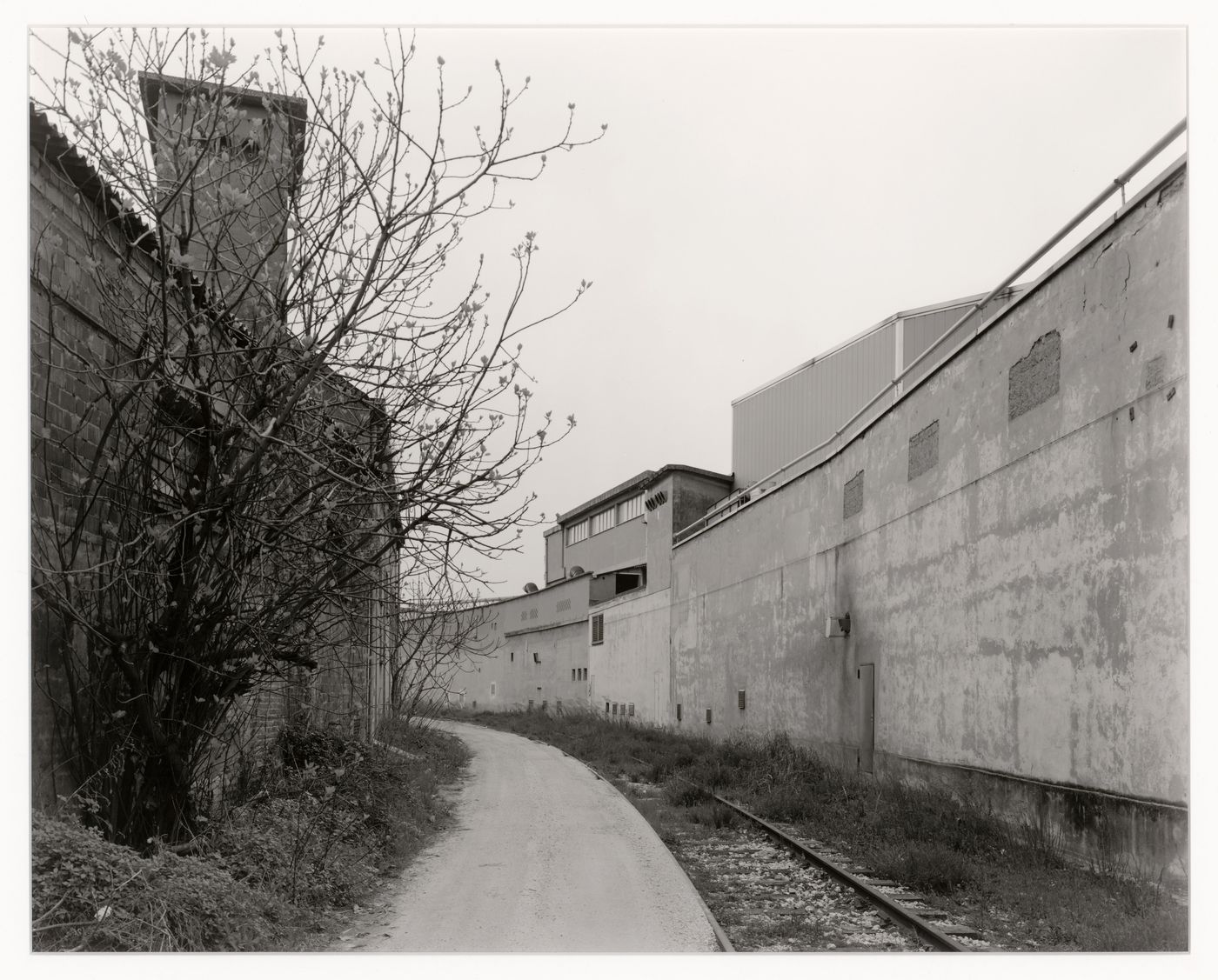 View of rails and a path with buildings on the right and left, corner of via delle machinne and via dell'elettricità,  Marghera, Italy