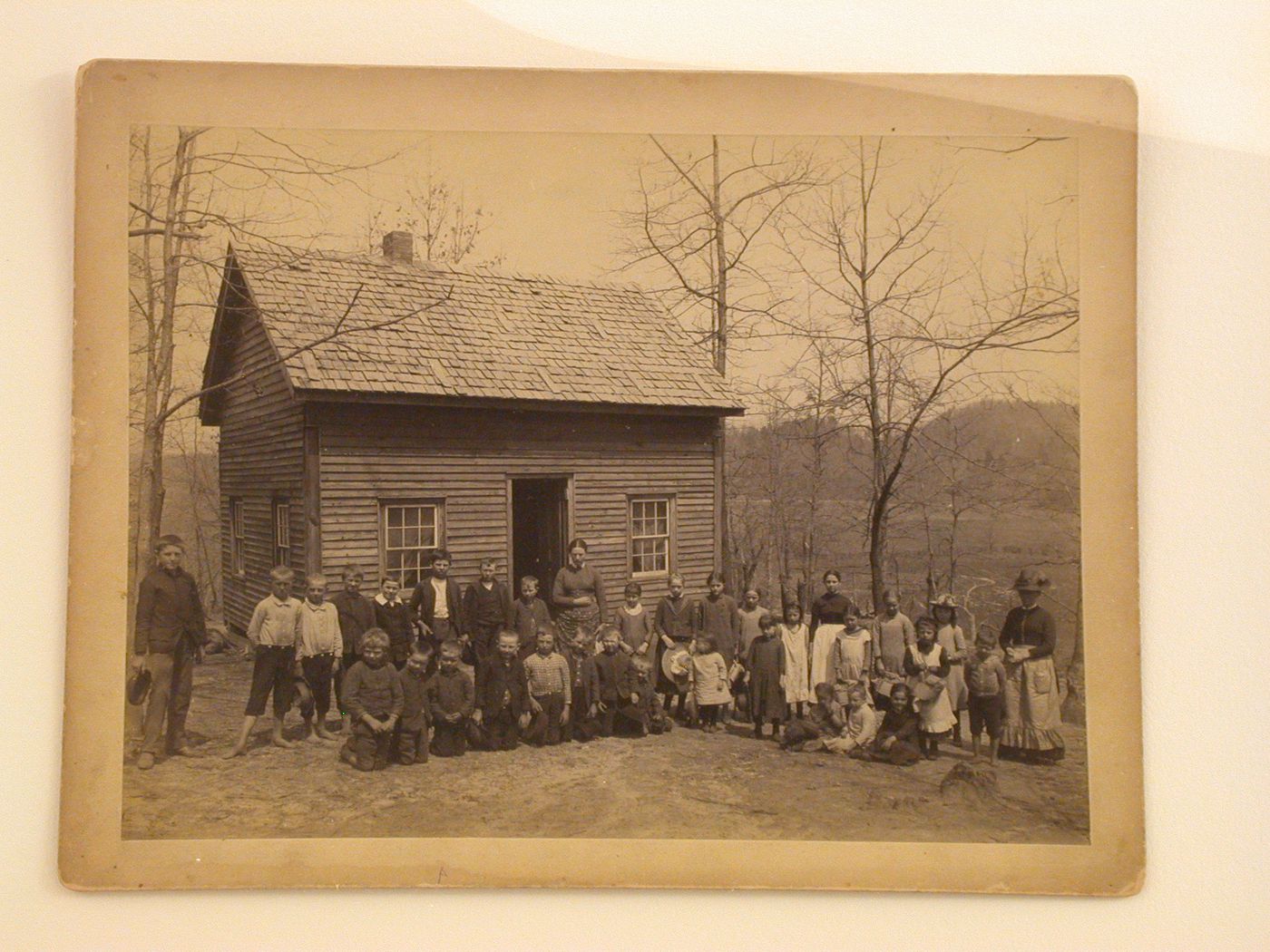 Wooden schoolhouse with students in yard