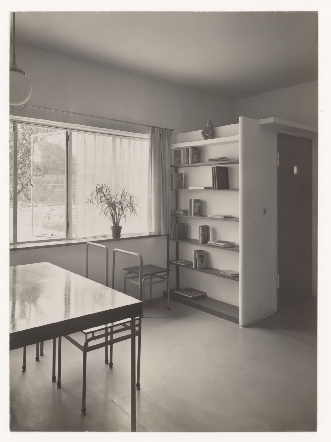 Interior view of the living room of House 8 showing a table, chairs and built-in bookshelf, Weissenhofsiedlung, Stuttgart, Germany