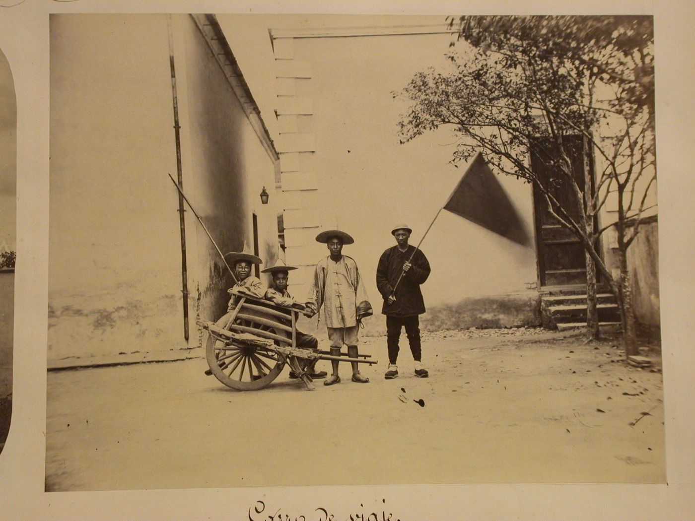 View of four men, a Chinese wheelbarrow and a flag