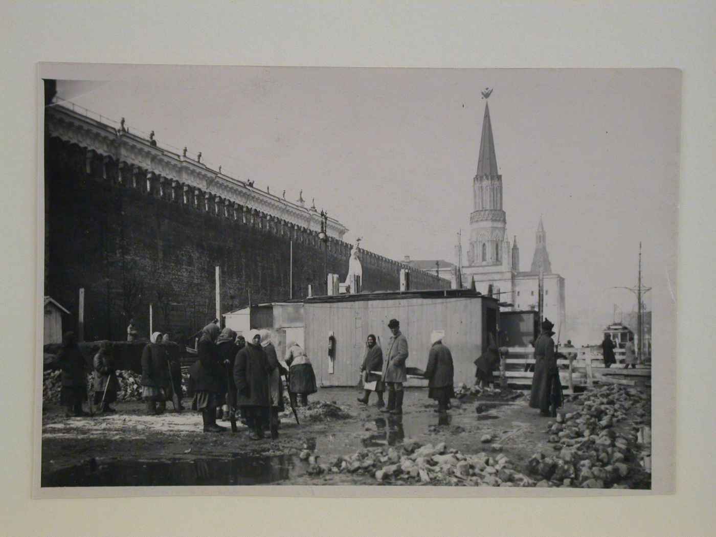 View of the construction site of the first wooden Lenin Mausoleum, showing women workers in the foreground, the access wings of the mausoleum and a monument in the centre, and the Nikol'skaia Tower (Nicholas Tower) in the background, Red Square, Moscow