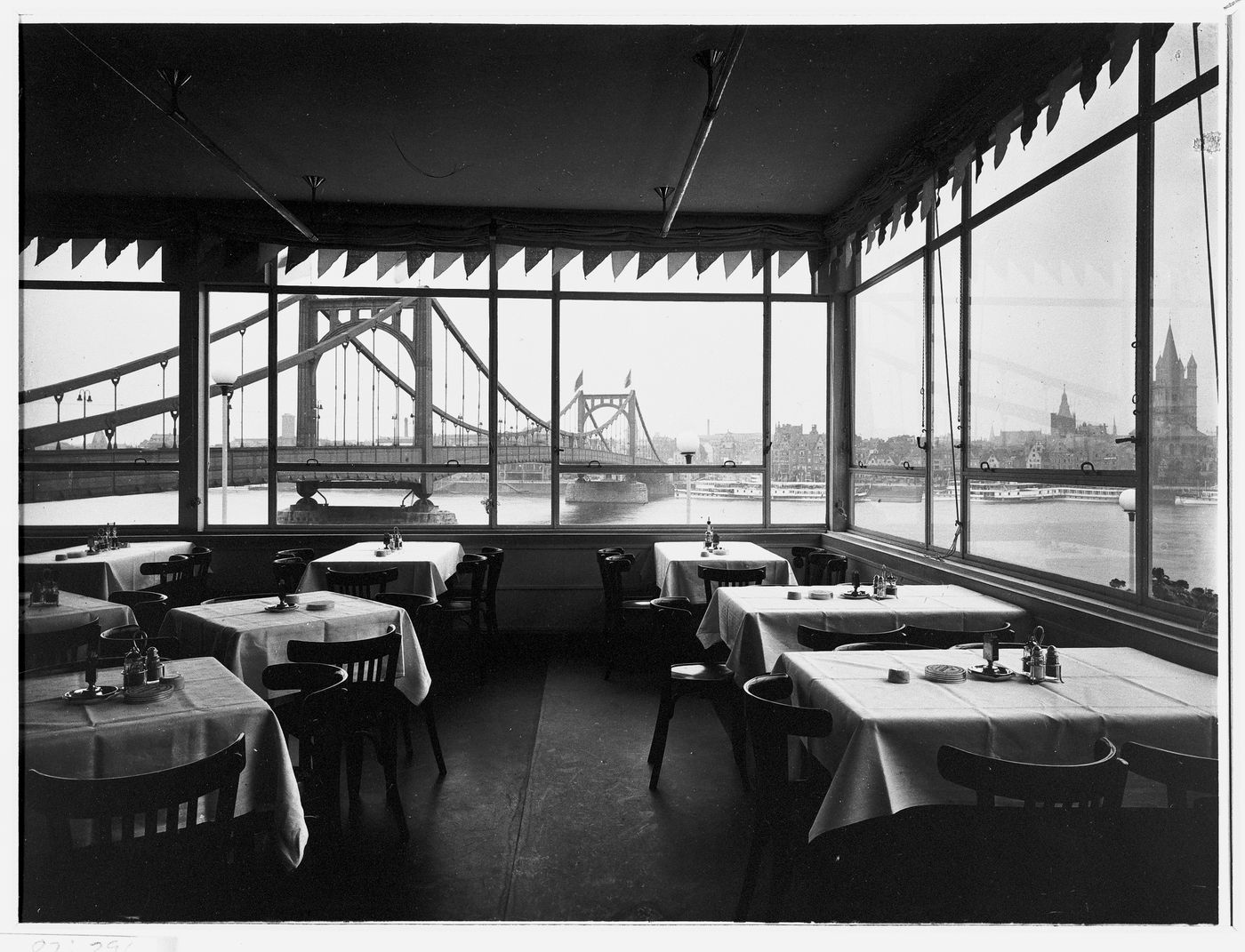 Interior view of Café Germania, Hehe Strasse, with view of suspension bridge, river and church through windows, Cologne,  Germany