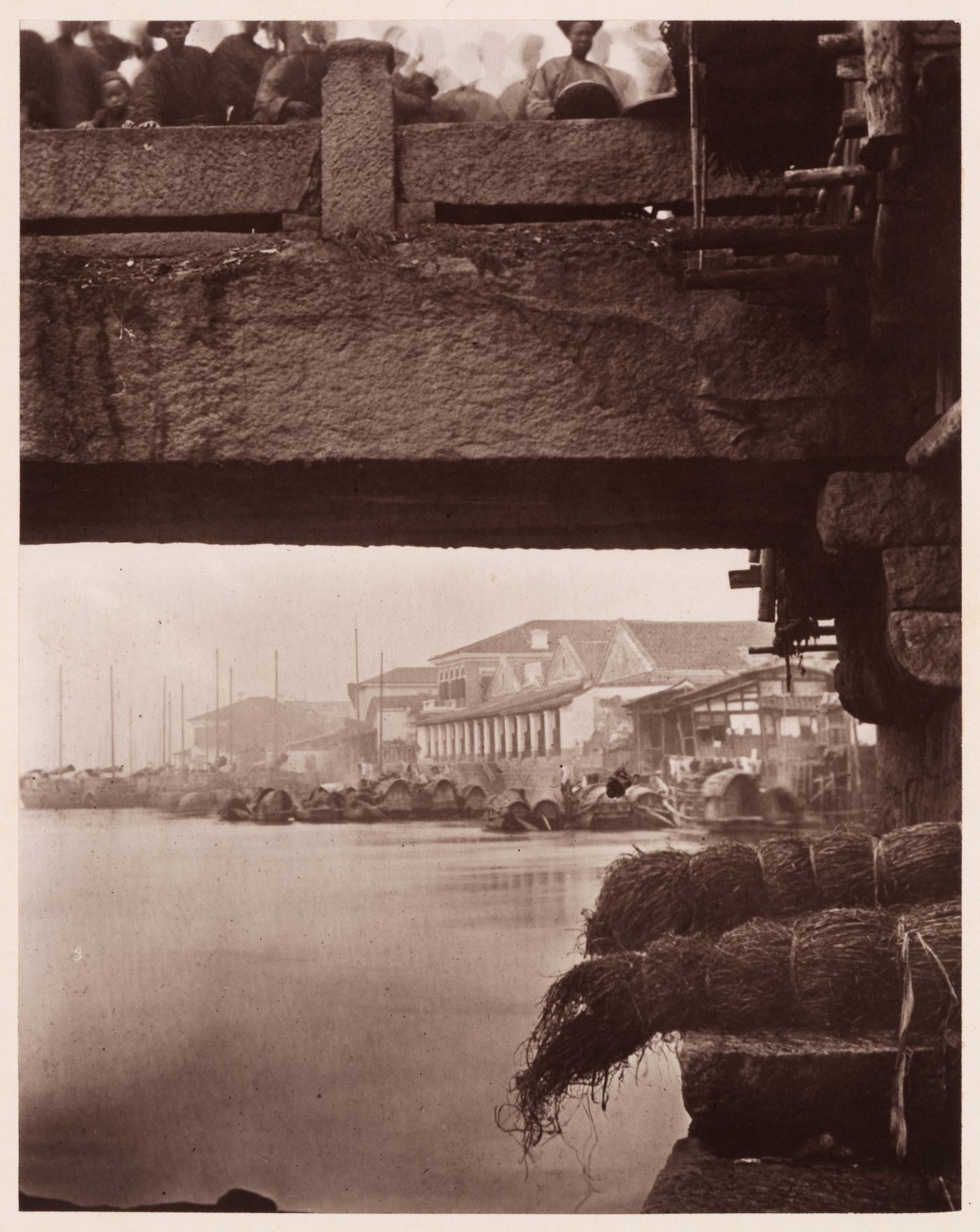 View of the bank of the Min River, with sampans and commercial buildings on the right and the Upper Bridge above, Foochow (now Fuzhou), China