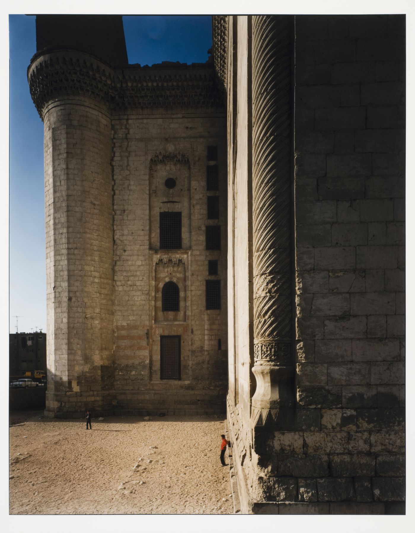 Mosque of Sultan Hassan, side view of building showing two corners and two figures on ground, Cairo, Egypt