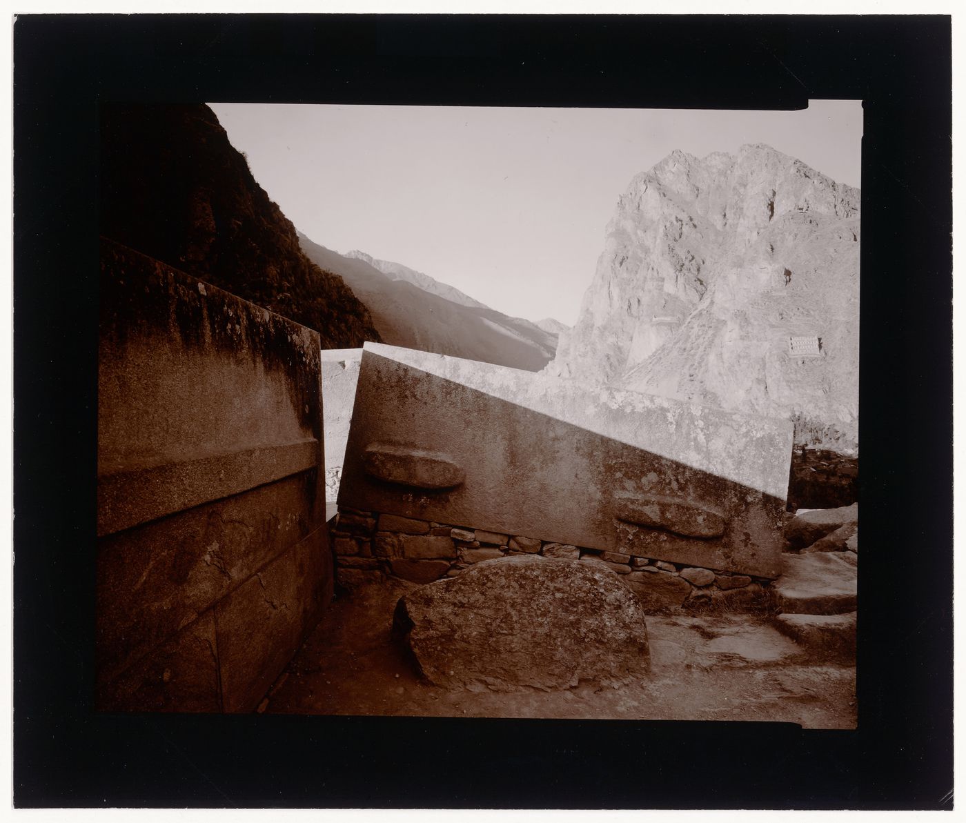 View of a large carved stone, possibly in the Sun Temple, with Pinkuylluna hill in the background, Ollantayambo, Peru