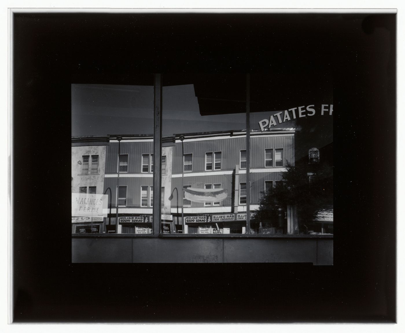 View of the windows of the restaurant at 4248 rue Saint-Denis showing the reflection of buildings across the street, Montréal, Québec