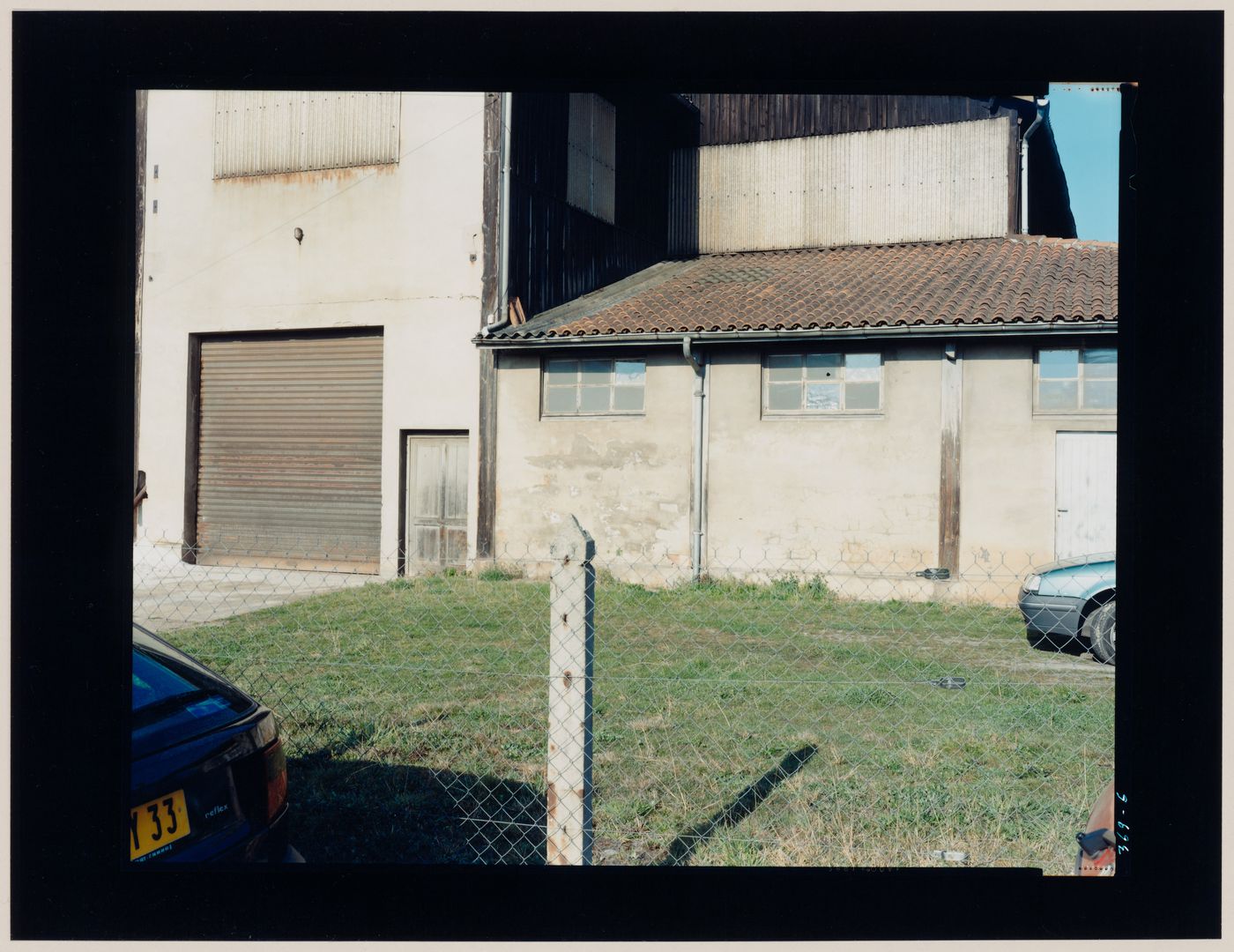 View of an agricultural building and a yard with grass, Sabres, France (from the series "In between cities")