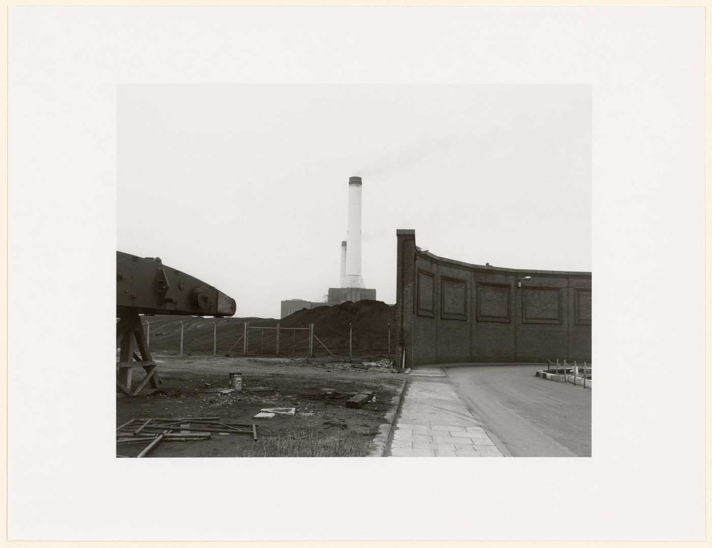 Tall smokestacks in background, brick wall with coffering patterns at right