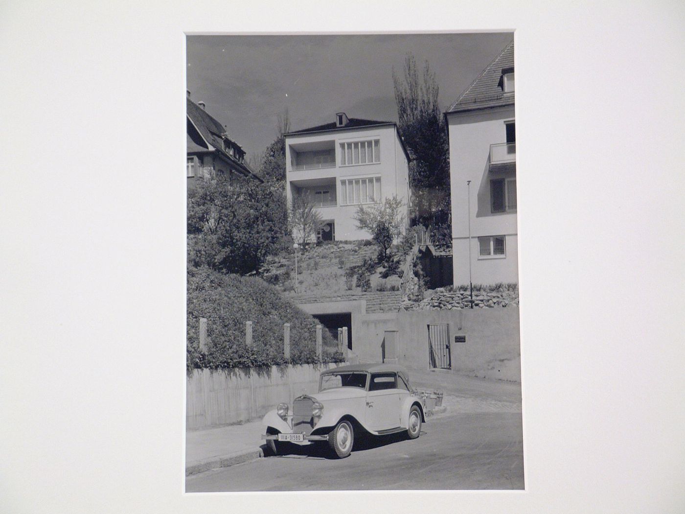 View of modern houses on steep slope above street, car in foreground, Germany