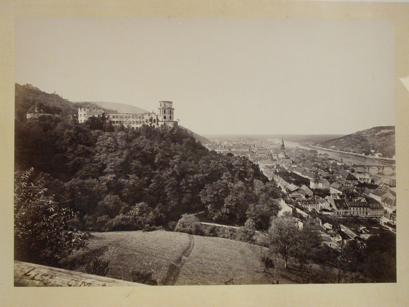 View from above hill above city of city and river with ruined castle in hill in middleground on left, Heidelberg [?], Germany