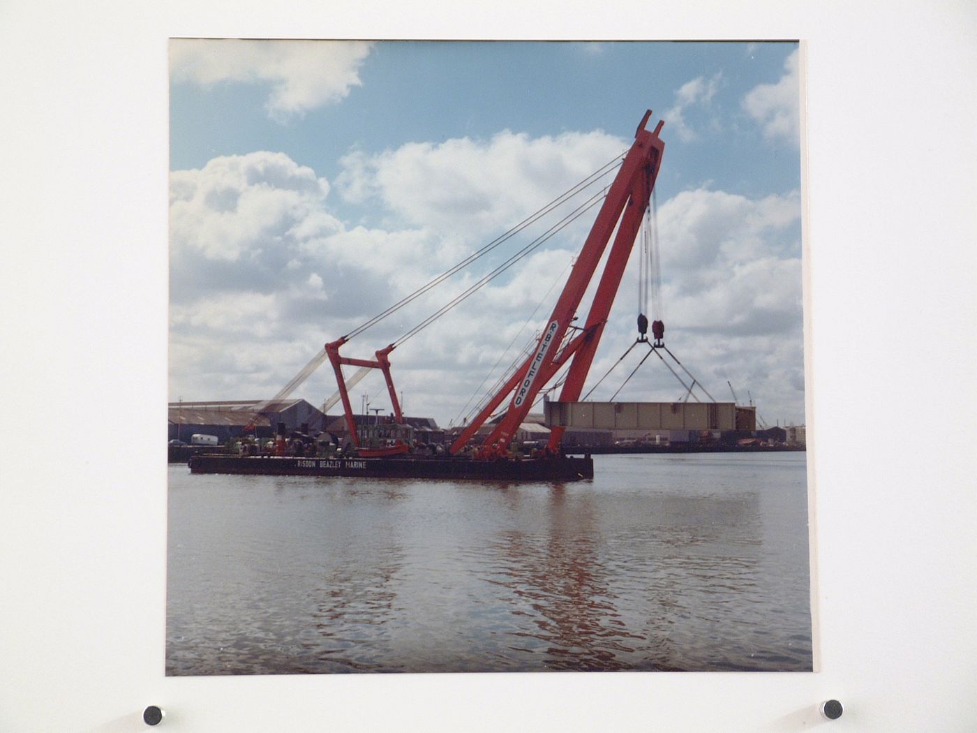 View of crane lifting a metal structure over water